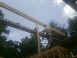 Carpenter setting a ridge beam over a new addition frame — Ice Dam Removal by Roofing Brothers in Lawtell