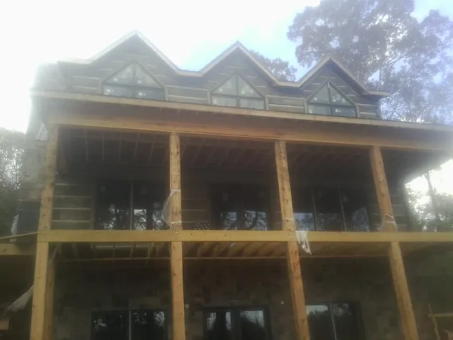 Dormers and porch framing on a large log home under construction — Roof Coating work by our crew in Lawtell