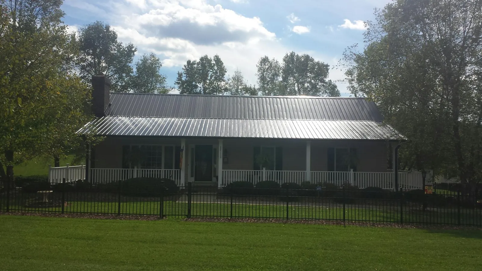 Gray metal roof on a brick ranch with a full width front porch in Lawtell