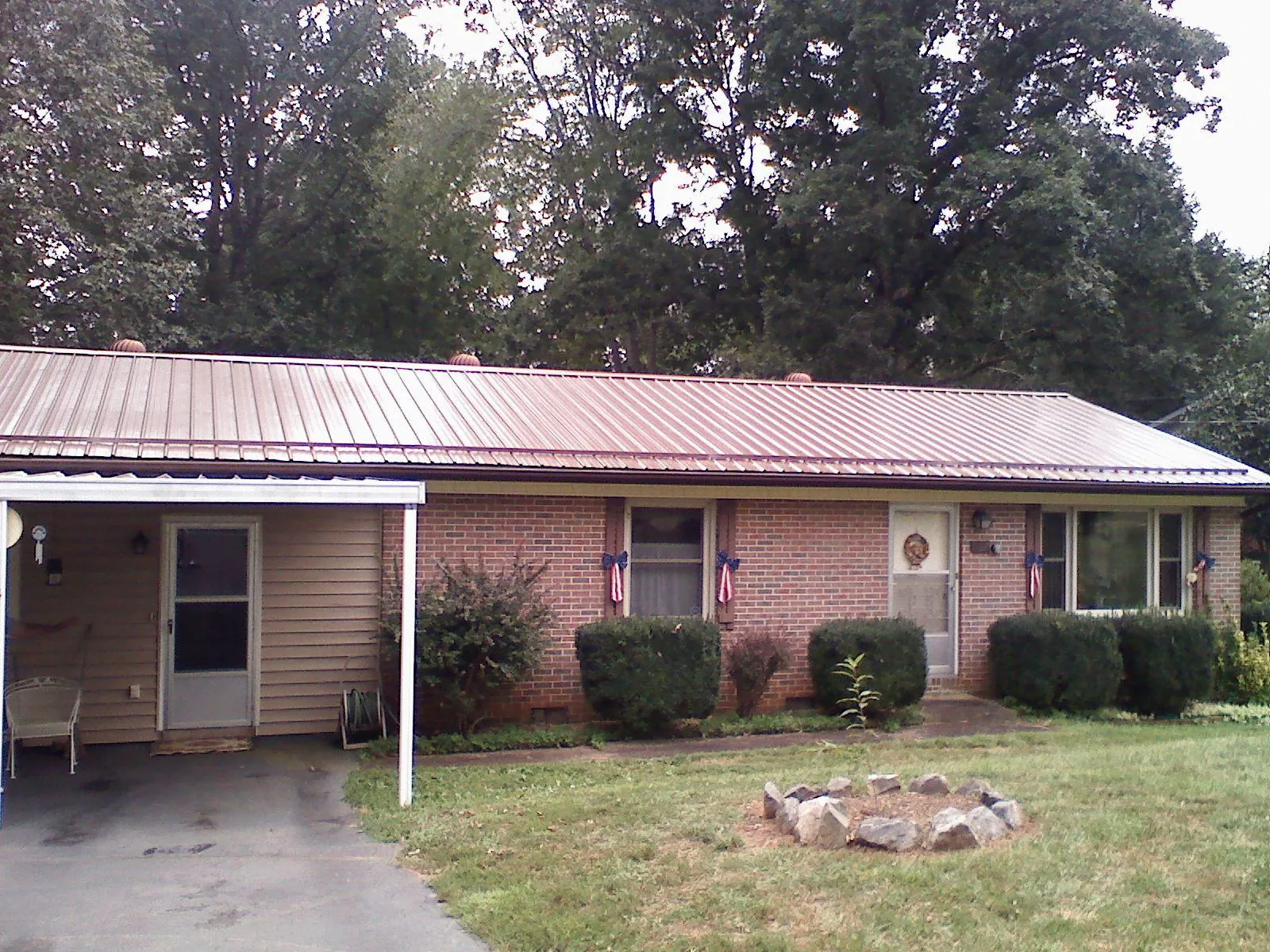 Bronze metal roof and carport on a brick ranch home — Roof Repair work by our crew in Lawtell