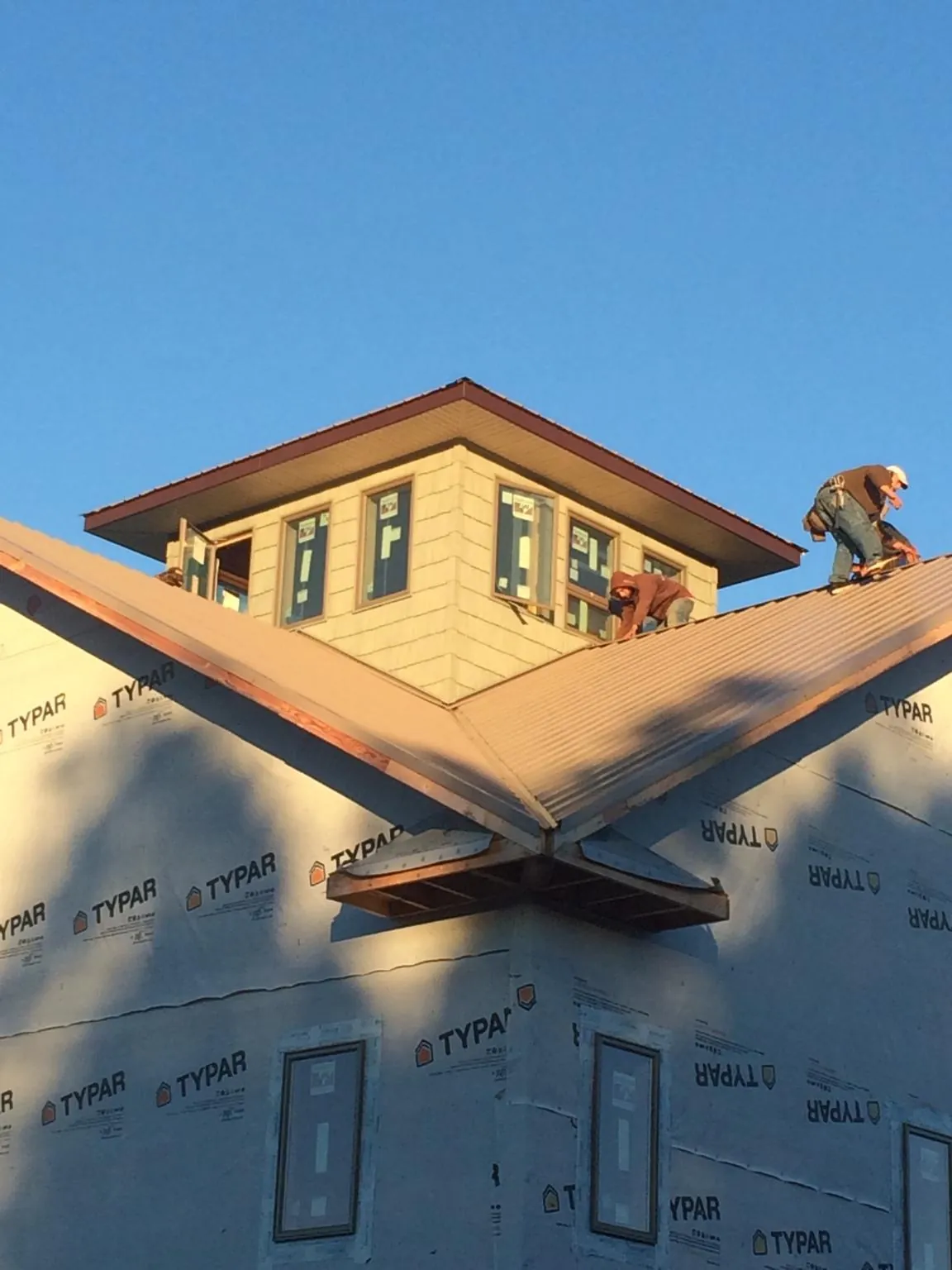 Roofers working around a rooftop cupola on a new metal roof at sunset — Roof Waterproofing in Lawtell by Roofing Brothers